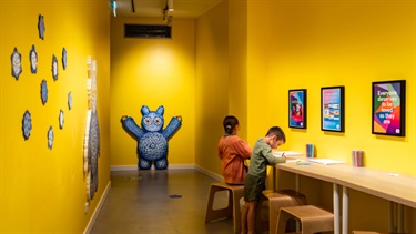 Two kids are sitting down at a bench colouring in.