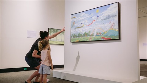 A woman is showing a young girl an artwork at Redcliffe Art Gallery