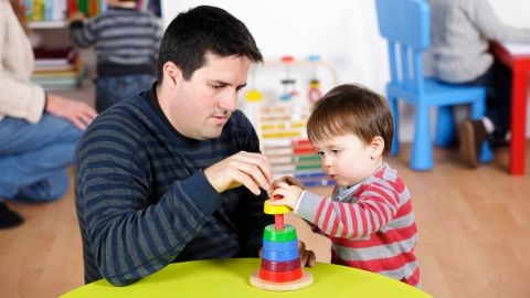 Man building coloured blocks with a child