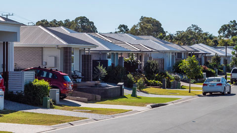 A suburban street with houses and parked cars