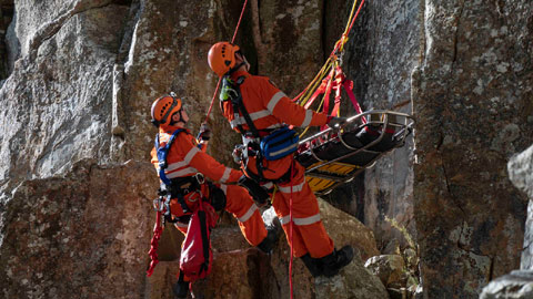 Two SES rescuers performing a cliff rescue, they're harnessed with a stretcher