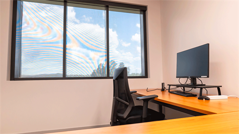 A desk with a computer and chair next to a window