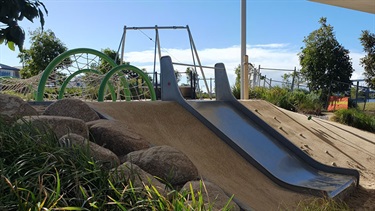 Children's playground including slide down embankment