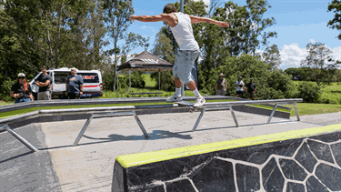 A man performing a skateboard trick on a rail.