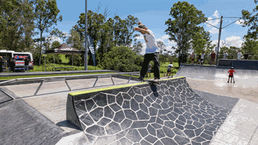 A man performing a skateboard trick at the new skate park upgrade.