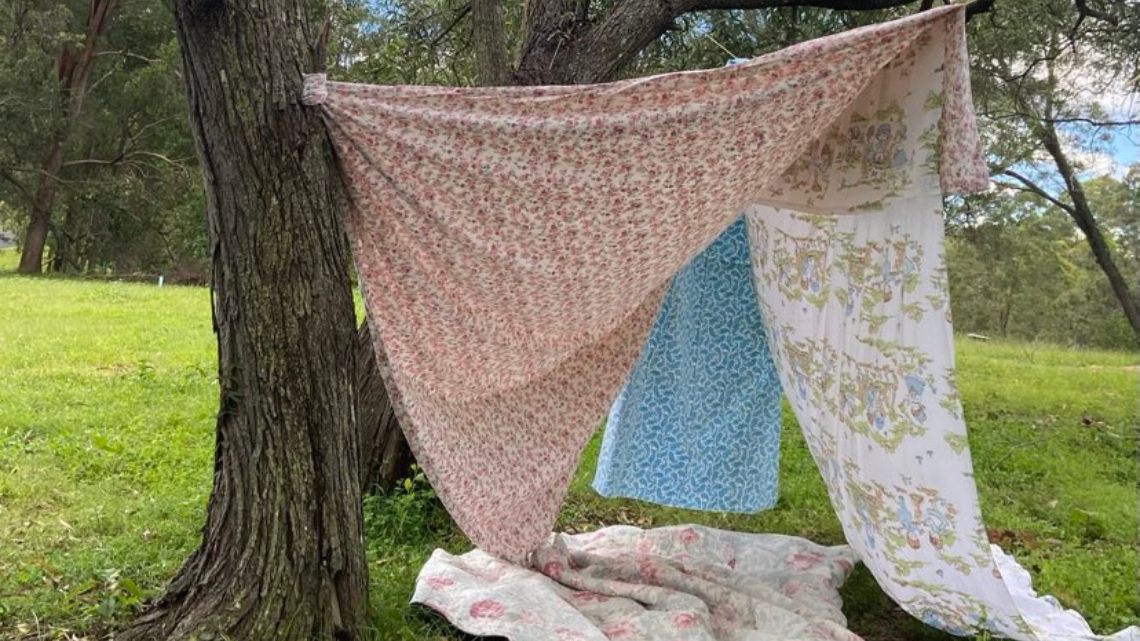 Four blankets hanging from a tree making a shelter