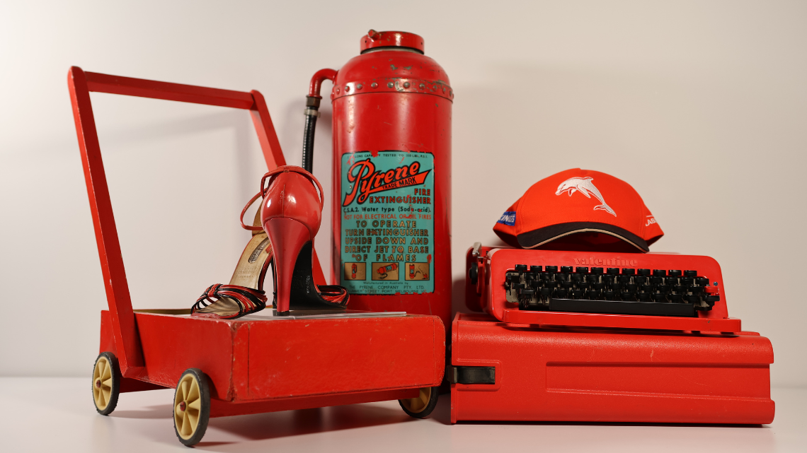 Red objects, including a pushcart, typewriter, hat, fire extinguisher and high heels