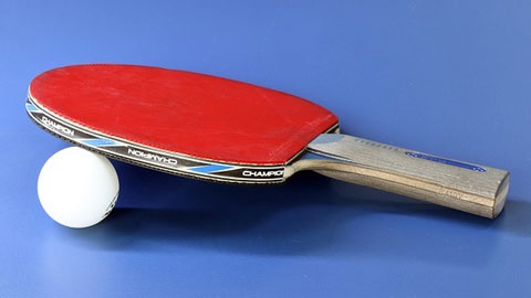 Table tennis paddle propped up by a ping pong ball