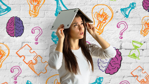 girl holding laptop over her head with a thinking expression against white wall with cartoons