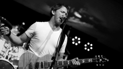 Image of Dean Porter signing and playing the guitar