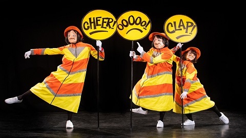 Three female characters dressed as lollipop ladies carrying reactive signs