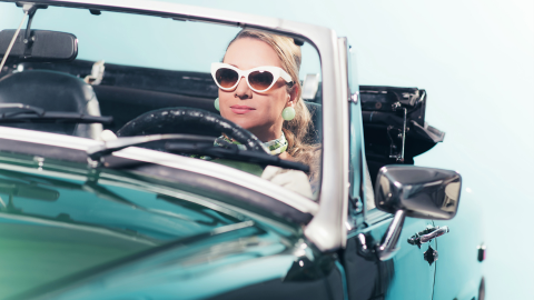 Welcome to the '60s: a decorative image of a woman in a convertible wearing sunglasses.