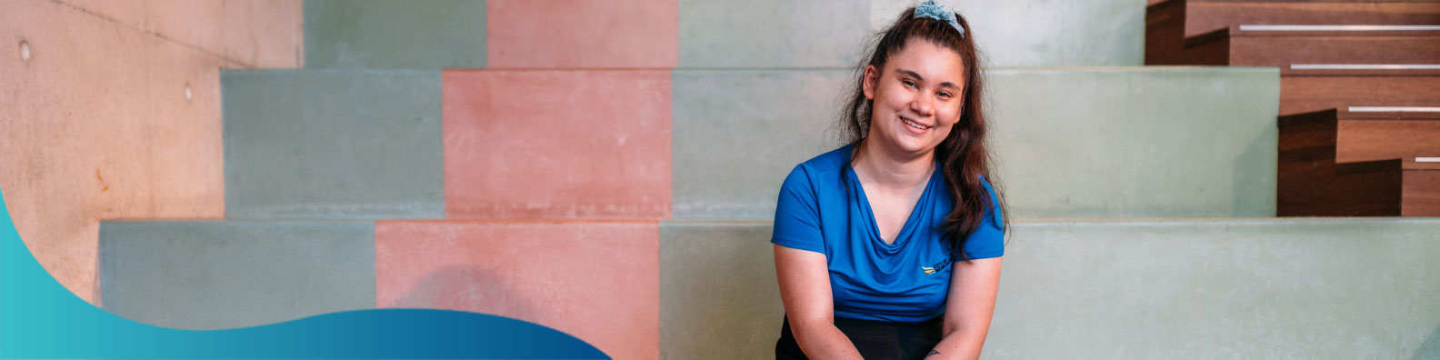 Girl in a blue shirt sitting on coloured stairs