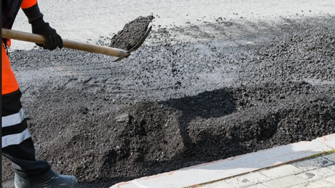 person shoveling road base