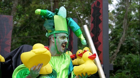 Man painted green holding large yellow rubber ducks