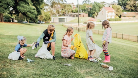 A group of young children picking up rubbish from a park