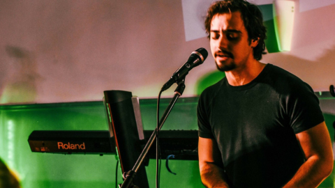 Image of David Carr singing into a microphone with a keyboard in the background