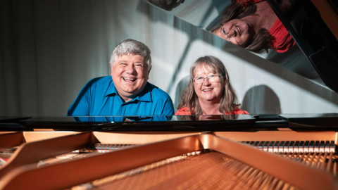 Enharmonie Chamber Ensemble - members of the ensemble sitting at a piano smiling to the camera.