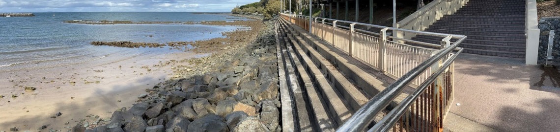 lots of rocks forming a seawall on the beach next to a pathway