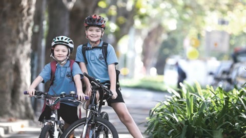 Two kids in blue school uniforms on their bikes