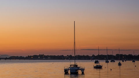 Pumicestone passage with the sun setting behind boats on the water