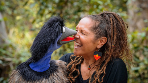 a lady holding a puppet laughing and smiling as the puppet is facing towards her