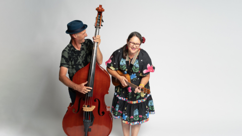 Against a white backdrop are the band Highs and Lows, one member is holding a ukulele and the other member is holding a cello.