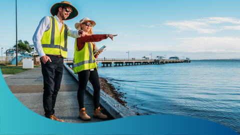 Two people in hi-vis pointing at the water